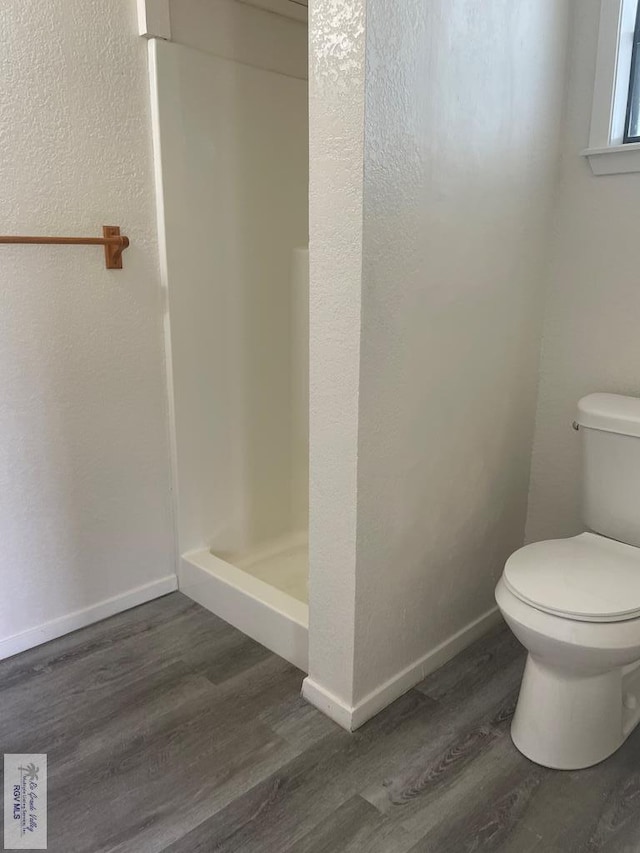 bathroom with a shower, hardwood / wood-style floors, and toilet