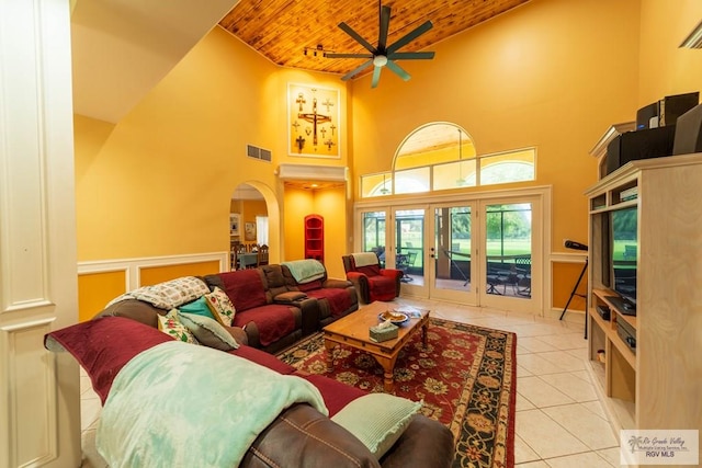living area featuring a towering ceiling, tile patterned floors, wooden ceiling, french doors, and a ceiling fan