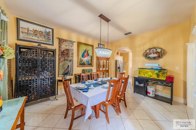dining room featuring visible vents, arched walkways, light tile patterned floors, and an inviting chandelier