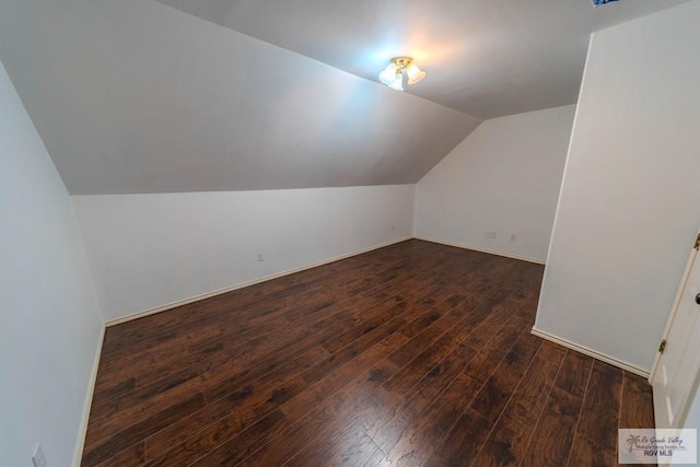 additional living space featuring baseboards, lofted ceiling, and hardwood / wood-style floors