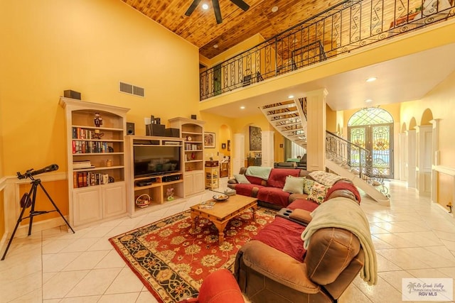 living area featuring arched walkways, light tile patterned floors, wooden ceiling, high vaulted ceiling, and stairs