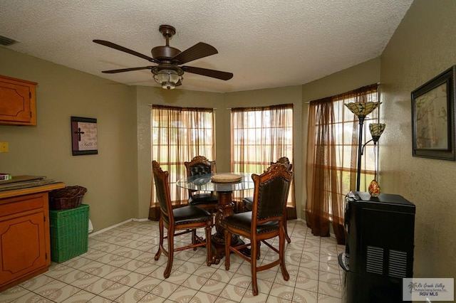 dining room with baseboards, a ceiling fan, visible vents, and a textured ceiling