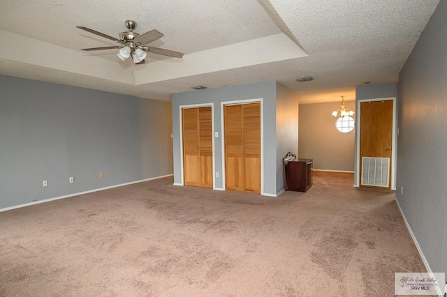 unfurnished bedroom featuring visible vents, a raised ceiling, two closets, and a textured ceiling