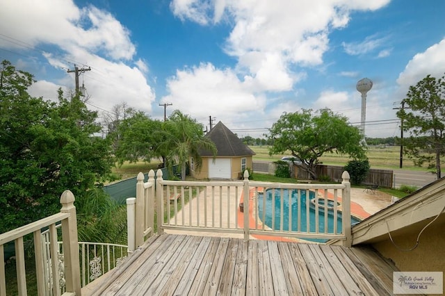 wooden deck with an outbuilding, a fenced in pool, fence, and a detached garage