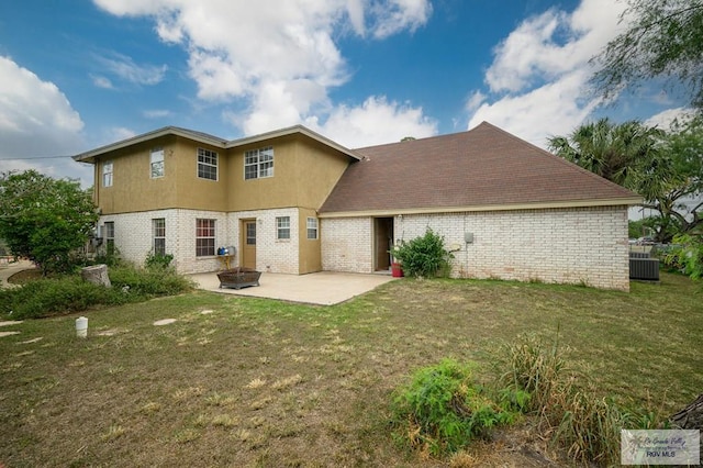 back of property with a patio, a lawn, and brick siding