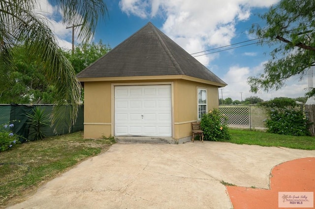 detached garage featuring fence and driveway