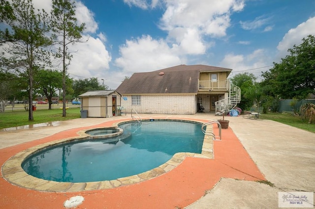 view of swimming pool with a pool with connected hot tub, stairs, an outbuilding, a storage unit, and a patio