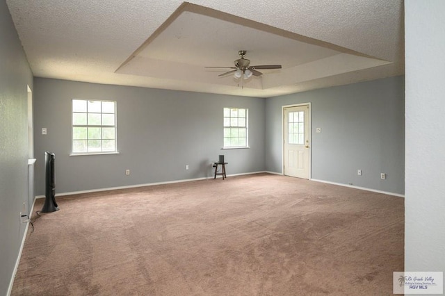 empty room with ceiling fan, baseboards, carpet, a textured ceiling, and a raised ceiling