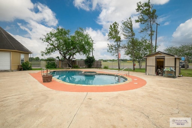 view of pool featuring a patio, a pool with connected hot tub, an outdoor structure, and fence