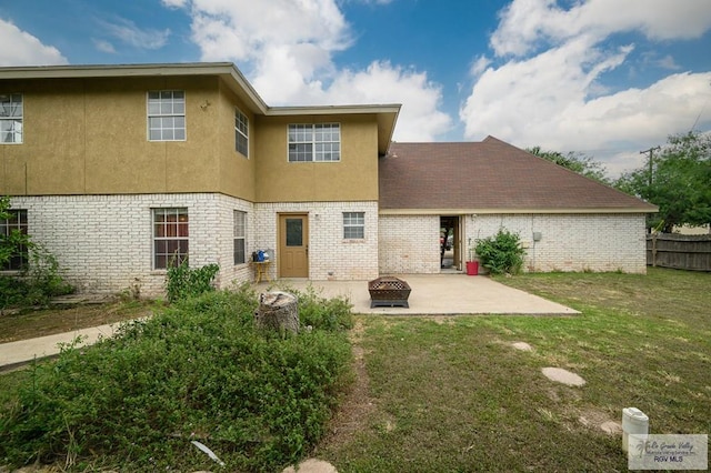 back of house featuring brick siding, a fire pit, and a patio