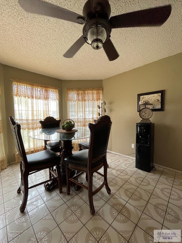 dining room with baseboards, a textured ceiling, light tile patterned flooring, and a ceiling fan