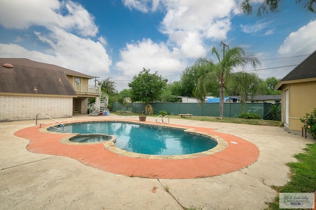 view of swimming pool featuring stairway, a pool with connected hot tub, a patio, and fence