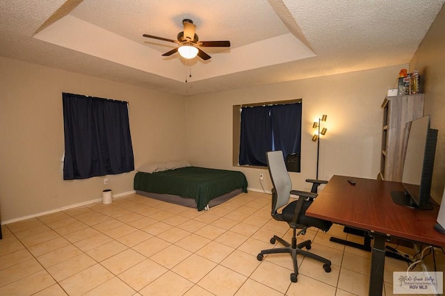 bedroom with light tile patterned floors, baseboards, ceiling fan, a textured ceiling, and a raised ceiling