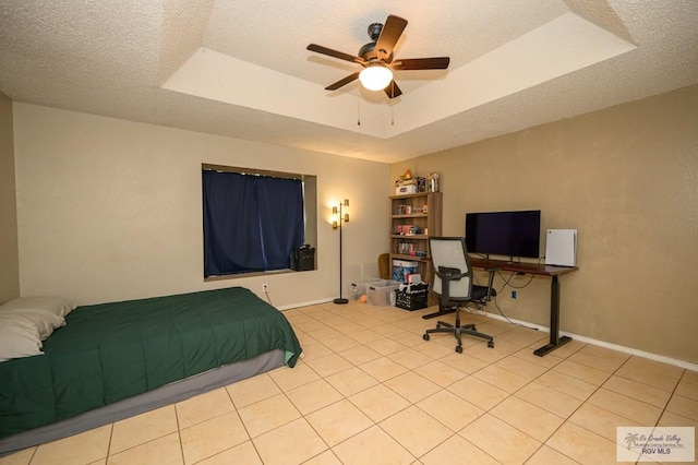 tiled bedroom featuring baseboards, a raised ceiling, a textured ceiling, and a ceiling fan