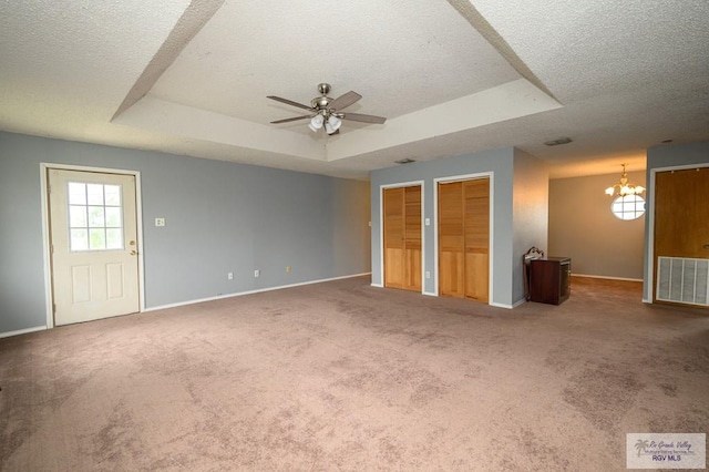 unfurnished bedroom with baseboards, visible vents, carpet floors, a tray ceiling, and multiple closets