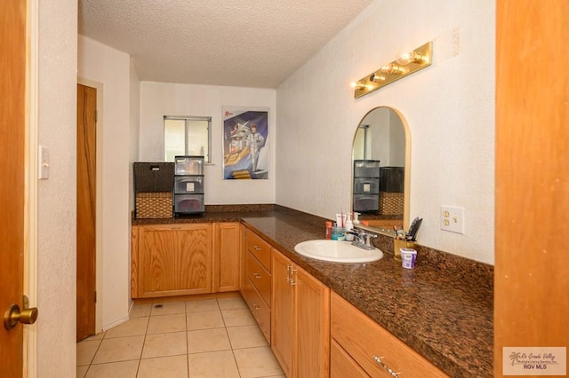 bathroom with tile patterned floors, a textured ceiling, and vanity