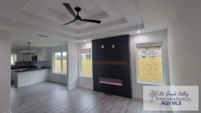 unfurnished living room with wood-type flooring, a tray ceiling, and ceiling fan