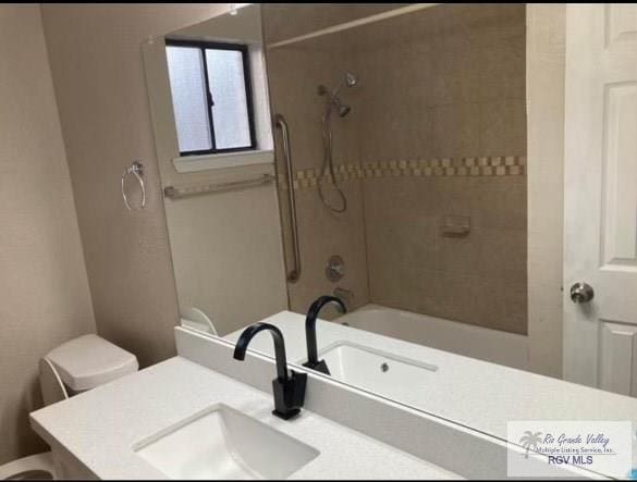 full bathroom featuring vanity, tiled shower / bath, and toilet