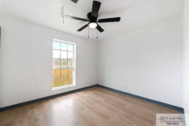 spare room with wood finished floors, ceiling fan, and baseboards
