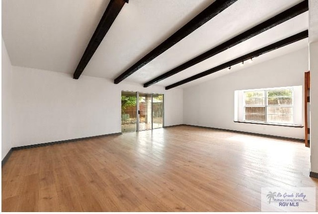 unfurnished living room with light wood-type flooring, baseboards, vaulted ceiling with beams, and a wealth of natural light