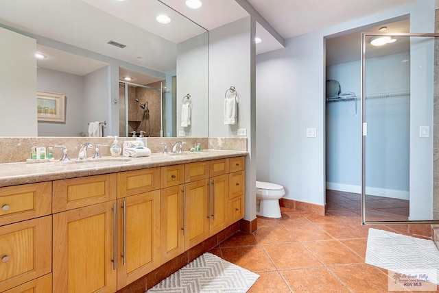 bathroom featuring tile patterned flooring, vanity, toilet, and walk in shower