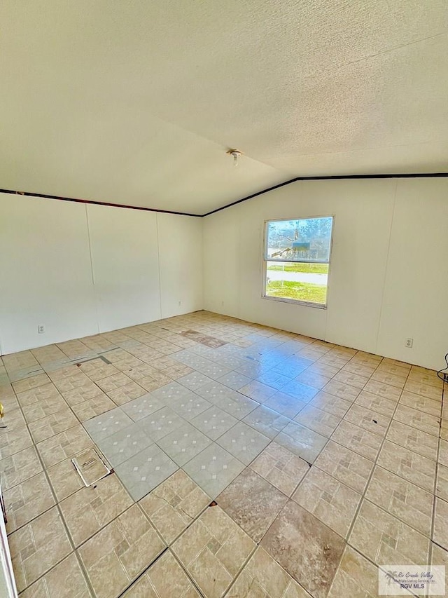 empty room featuring vaulted ceiling and a textured ceiling