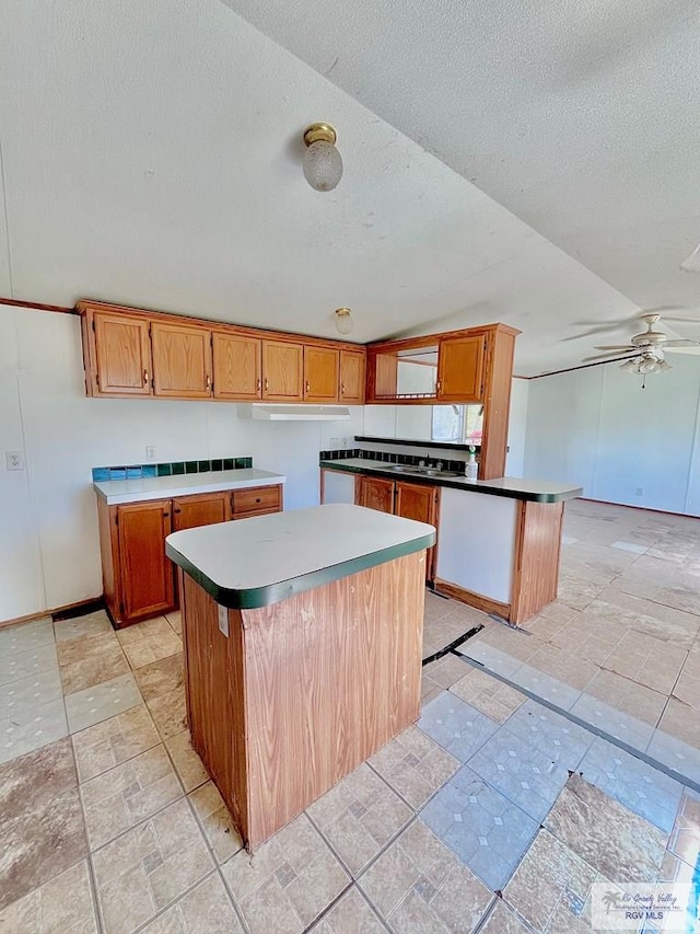 kitchen with brown cabinets, a kitchen island, and light countertops