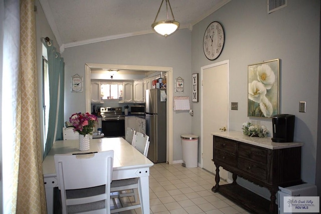 kitchen with stainless steel appliances, pendant lighting, vaulted ceiling, light tile patterned floors, and ornamental molding