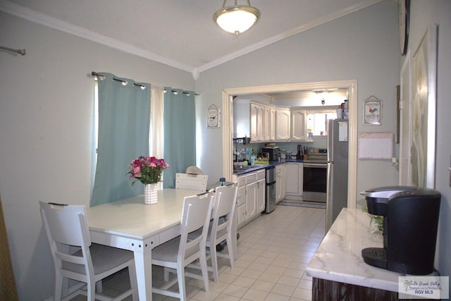 tiled dining area featuring crown molding and lofted ceiling