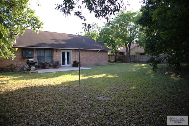 rear view of house with a lawn, french doors, and a patio