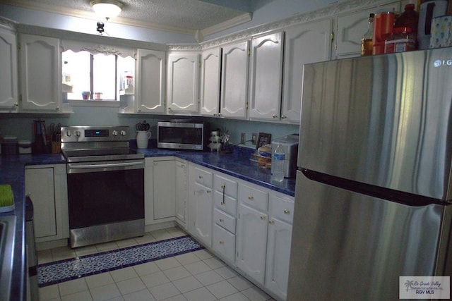 kitchen featuring light tile patterned flooring, white cabinetry, a textured ceiling, and appliances with stainless steel finishes