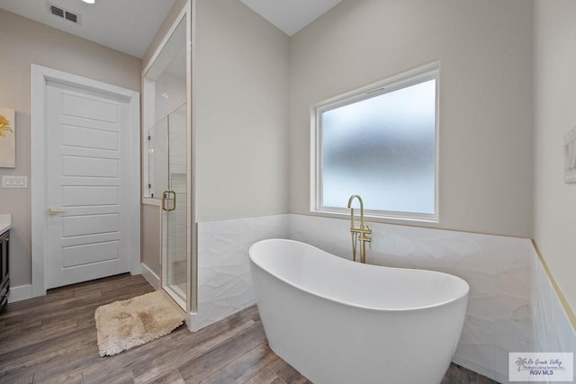 bathroom featuring visible vents, vanity, a shower stall, and wood finished floors