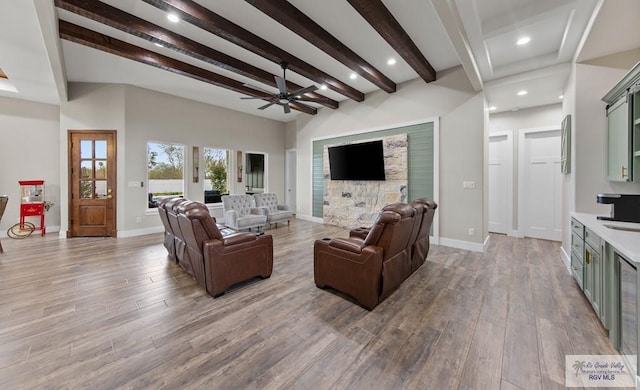 living area featuring a ceiling fan, beam ceiling, baseboards, and wood finished floors