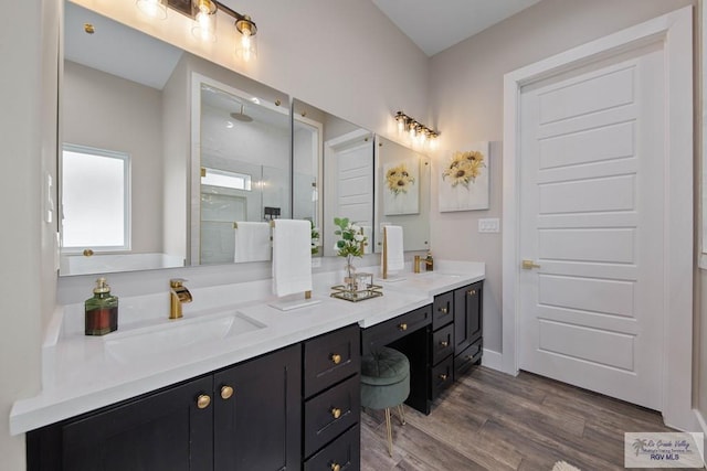 full bathroom with wood finished floors, a sink, a shower stall, and double vanity