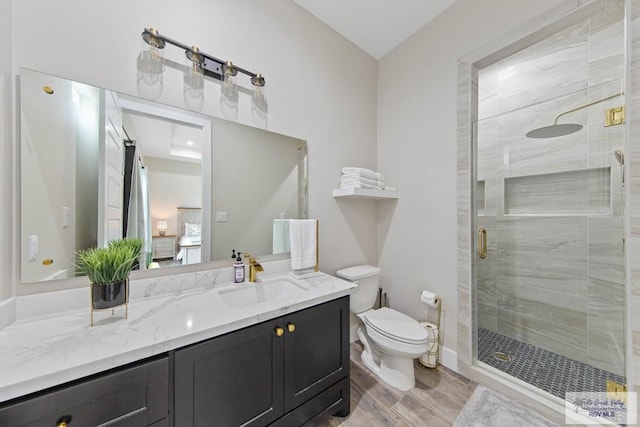 ensuite bathroom featuring toilet, a stall shower, ensuite bathroom, and vanity