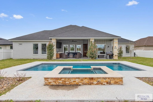 back of house featuring a yard, board and batten siding, a ceiling fan, a fenced backyard, and an outdoor living space