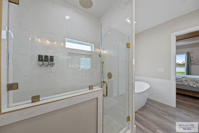 ensuite bathroom with a wainscoted wall, a freestanding tub, a stall shower, and ensuite bath