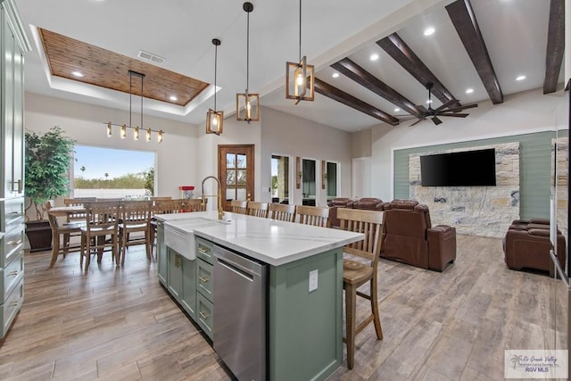 kitchen with dishwasher, a tray ceiling, light wood finished floors, and a sink