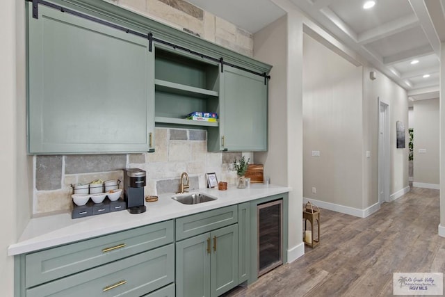 kitchen featuring green cabinets, beverage cooler, backsplash, and a sink