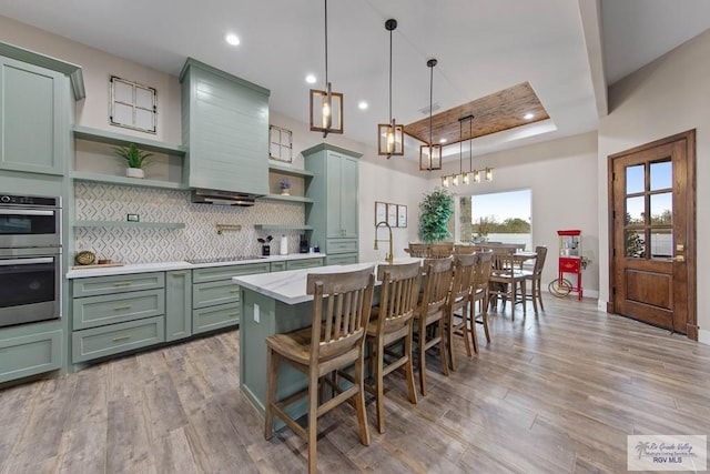 kitchen with double oven, premium range hood, green cabinets, and open shelves