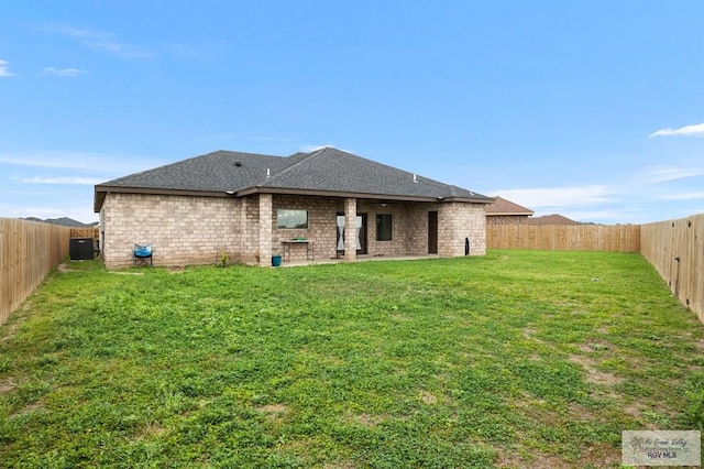 rear view of house with central air condition unit and a lawn