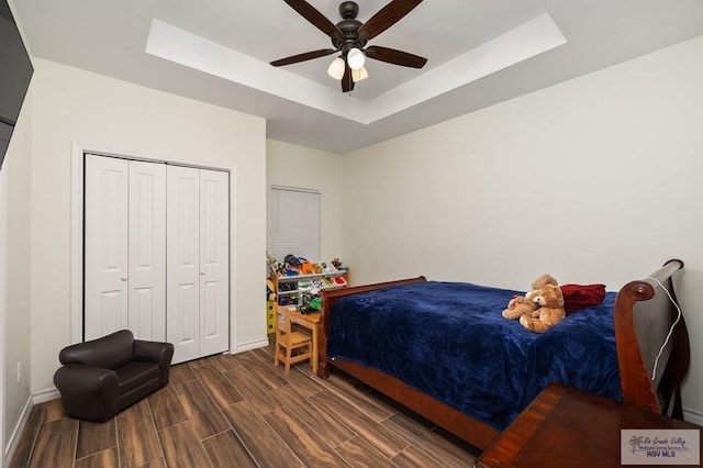 bedroom with a closet, ceiling fan, and a tray ceiling