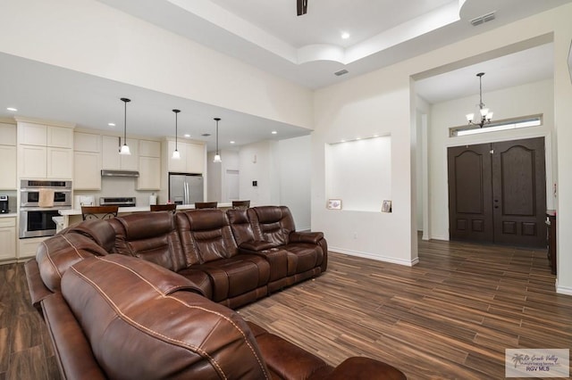 living room featuring dark hardwood / wood-style flooring, a chandelier, and a tray ceiling