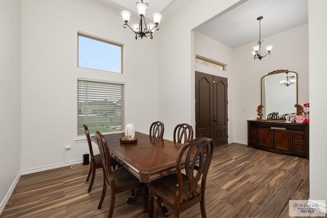 dining space featuring an inviting chandelier, a towering ceiling, and dark hardwood / wood-style flooring