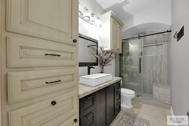 bathroom featuring tile patterned floors, vanity, toilet, and a shower with shower door