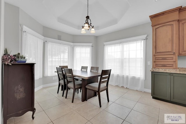 dining area with a notable chandelier, light tile patterned flooring, and a tray ceiling