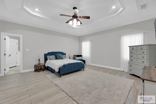 bedroom featuring a raised ceiling, light hardwood / wood-style flooring, and ceiling fan