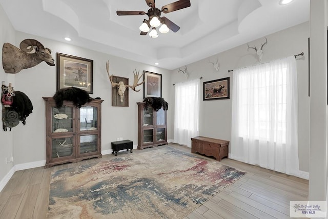 miscellaneous room featuring a raised ceiling, ceiling fan, and light wood-type flooring