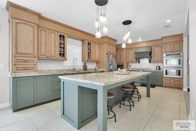 kitchen featuring light stone countertops, appliances with stainless steel finishes, a center island, and custom range hood