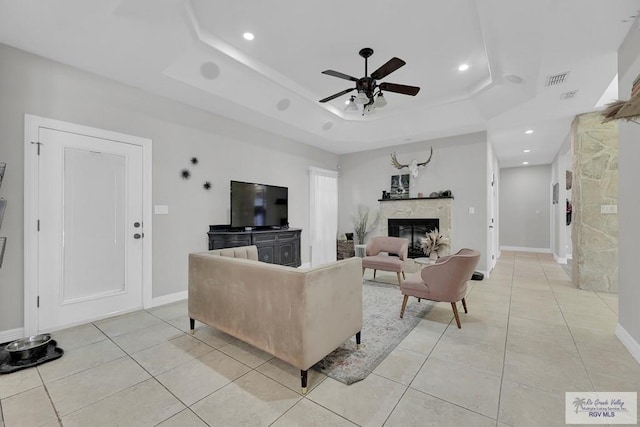 tiled living room with a tray ceiling and ceiling fan